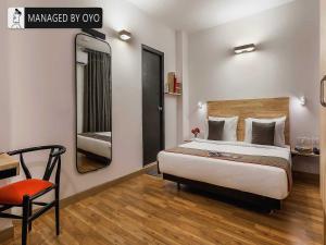1 dormitorio con cama, silla y espejo en Townhouse Greater Kailash Near Kailash Colony Metro Station en Nueva Delhi