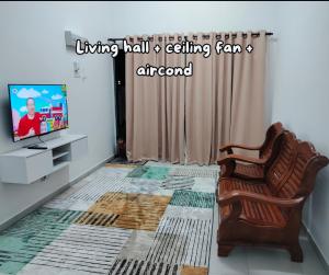a living room with a chair and a television at Umar's Lodge in Bemban