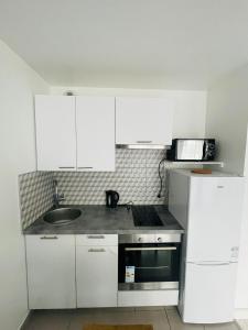 uma cozinha com armários brancos, um lavatório e um micro-ondas em Studio 2 pers, Villemomble disneyland Porte de la villette em Villemomble