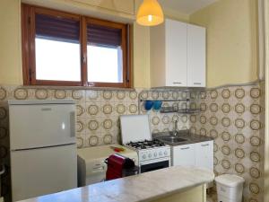 a kitchen with a stove and a white refrigerator at Appartamento Ciclamini in Campomarino