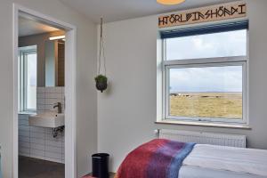 baño con cama, lavabo y ventana en Midgard Base Camp, en Hvolsvöllur