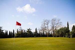 un campo de golf con bandera roja en el green en AIGUESVERDS HomeStay By Turismar, en Reus
