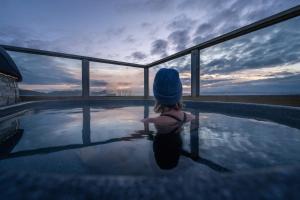 una niñita sentada en una piscina viendo la puesta de sol en Midgard Base Camp, en Hvolsvöllur