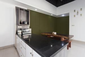 eine Küche mit grünen Wänden und einer schwarzen Arbeitsplatte in der Unterkunft Maja Villa Batubelig by Pramana Villas in Canggu