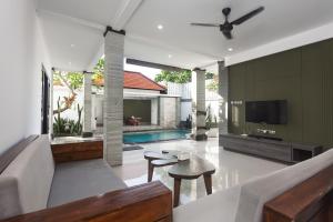 ein Wohnzimmer mit einem Sofa, einem TV und einem Pool in der Unterkunft Maja Villa Batubelig by Pramana Villas in Canggu