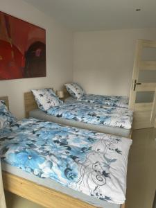 two beds with blue and white blankets and pillows at Apartamenty Monik Świętochłowice in Świętochłowice