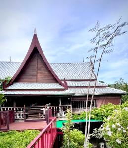 una casa con terraza roja y techo en MrT Riverside Sampran มิสเตอร์ที โฮมสเตย์-การเวก, en Sam Phran