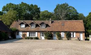 une grande maison en briques avec des portes blanches et une allée. dans l'établissement Maisons de campagne au calme en Sologne pour groupe avec piscine - proche de Paris, à Brinon-sur-Sauldre