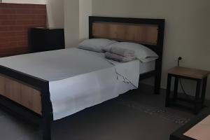 a bedroom with a large white bed and a table at Apartaestudio 301 velódromo in Medellín