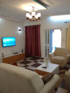 sala de estar con 2 sofás y TV en HOUSE SOS, en Abomey-Calavi