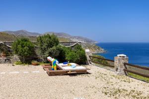 a chaise lounges on a hill overlooking the ocean at Aegean View - Seaside Apartment in Syros in Azolimnos