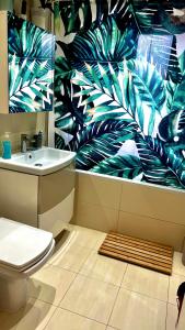 baño con aseo y un mural de hojas en Comfy apartment, en Londres