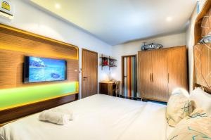 1 dormitorio con 1 cama y TV en la pared en The Title Boutique Phuket, en Rawai Beach