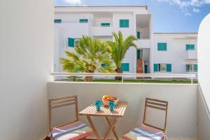 una mesa y sillas en un balcón con un edificio en Prainha Paradise - Algarve, en Alvor