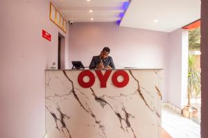 a man sitting at a counter with theovo sign on it at OYO 817 Hotel Garden Flower in Kathmandu