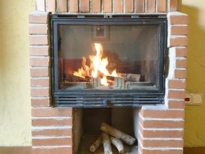 a brick fireplace with a fire in it at Alojamientos La Dehesa in El Berrueco