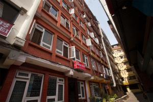 un bâtiment rouge avec des fenêtres blanches sur une rue dans l'établissement OYO 814 Machhapuchhre Hotel, à Katmandou