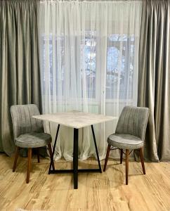 a table and two chairs in front of a window at ИП.МЕДИНА in Taraz