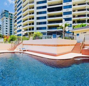 an outdoor swimming pool with buildings in the background at Seven @Aquarius in Cairns