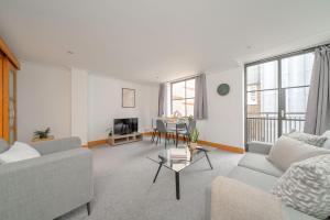ein Wohnzimmer mit einem Sofa und einem Tisch in der Unterkunft Holborn - 2BR Near Covent Garden -CityApartmentStay in London