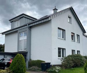 uma casa branca com um telhado preto em Helles ruhiges Appartement im Grünen em Dortmund