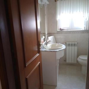 baño con lavabo, aseo y puerta en Terra Mista Alojamento Local, en Gouveia
