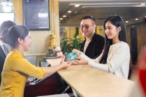 a woman is handing a gift to another woman at Hoang Son Peace Hotel in Ninh Binh