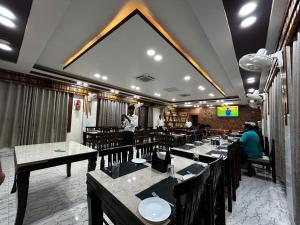a dining room with tables and a man on a phone at The Heritage in Dumka