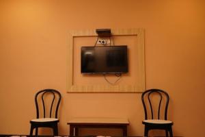 Cette chambre dispose de 2 chaises et d'une télévision murale. dans l'établissement Hotel Shubh Shree Bilaspur, à Bilāspur