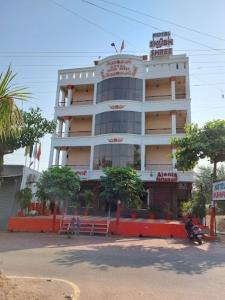 duży biały budynek z drzewami przed nim w obiekcie Hotel Shubh Shree Bilaspur w mieście Bilaspur
