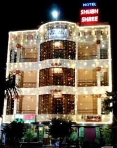 un edificio illuminato con un cartello di fronte di Hotel Shubh Shree Bilaspur a Bilaspur