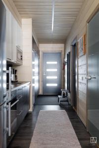 un couloir avec une porte menant à une cuisine avec un tapis dans l'établissement Ellivuori Chalet Moisio, à Sastamala