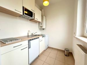 una cocina con armarios blancos y fregadero en StayRoom Apartments I "Woody5" neben Donaulände en Linz
