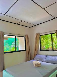 a bedroom with two windows and a bed in it at Green Garden Beach Resort, Sipalay in Sipalay