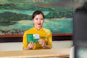 a woman standing at a table holding a book at Hoang Son Peace Hotel in Ninh Binh