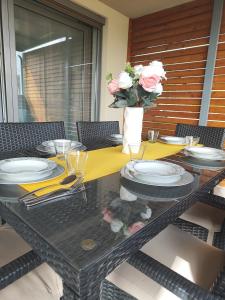 una mesa con platos y un jarrón de flores. en Family apartment Moravske Toplice en Moravske-Toplice