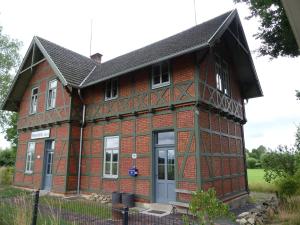 ein altes rotes Backsteinhaus mit grauer Tür in der Unterkunft Ferienwohnung Bahnhof 1892 in Meeder