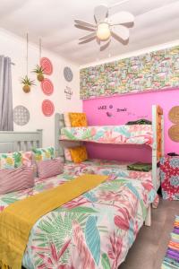 2 camas en una habitación con paredes rosas y coloridas en Cape Agulhas BACKPACKERS, en Struisbaai