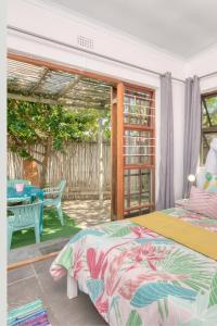 1 dormitorio con 1 cama y patio con mesa en Cape Agulhas BACKPACKERS, en Struisbaai
