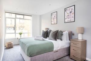 a white bedroom with a large bed and a window at Marylebone - Wimpole Street - CityApartmentStay in London