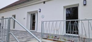 a white building with a gate and a door at Ferienwohnungen SATKULA in Crostwitz