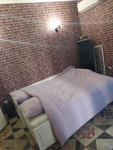 um quarto com uma parede de tijolos e uma cama com lençóis roxos em Studio maillane em Maillane