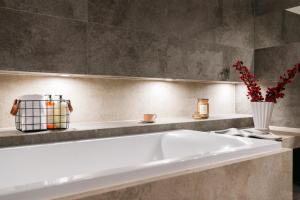 Una bañera blanca en un baño con un jarrón de flores. en Boho Lofts - LoftAffair, en Cracovia 123 fotos más