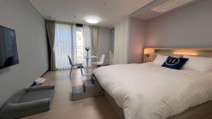 a bedroom with a bed and a chair and a table at 호야스테이 Hoya stay in Yeosu