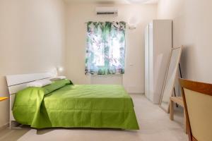 - une chambre avec un lit vert et une fenêtre dans l'établissement La Casa di Mammalina A, à Ostuni