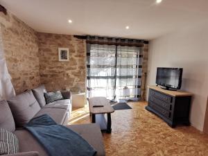 a living room with a couch and a tv at Gîte Corrézien 3 pers. Piscine chauffée in Chamboulive