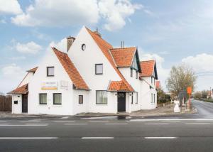 a white building with an orange roof on a street at Zeegalm Bungalows in Middelkerke
