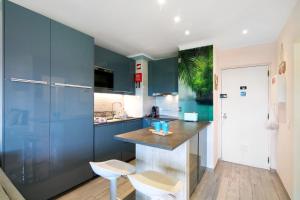 a kitchen with blue cabinets and white stools at Olilou - Seaview Studio in Portimão