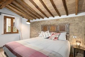 een slaapkamer met een groot bed en een stenen muur bij Casa Vesta in San Gimignano