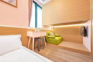 1 dormitorio con cama, escritorio y silla verde en Lemon Hotel - Metro Line 1 Line 7 Changshu Road 200 meters en Shanghái